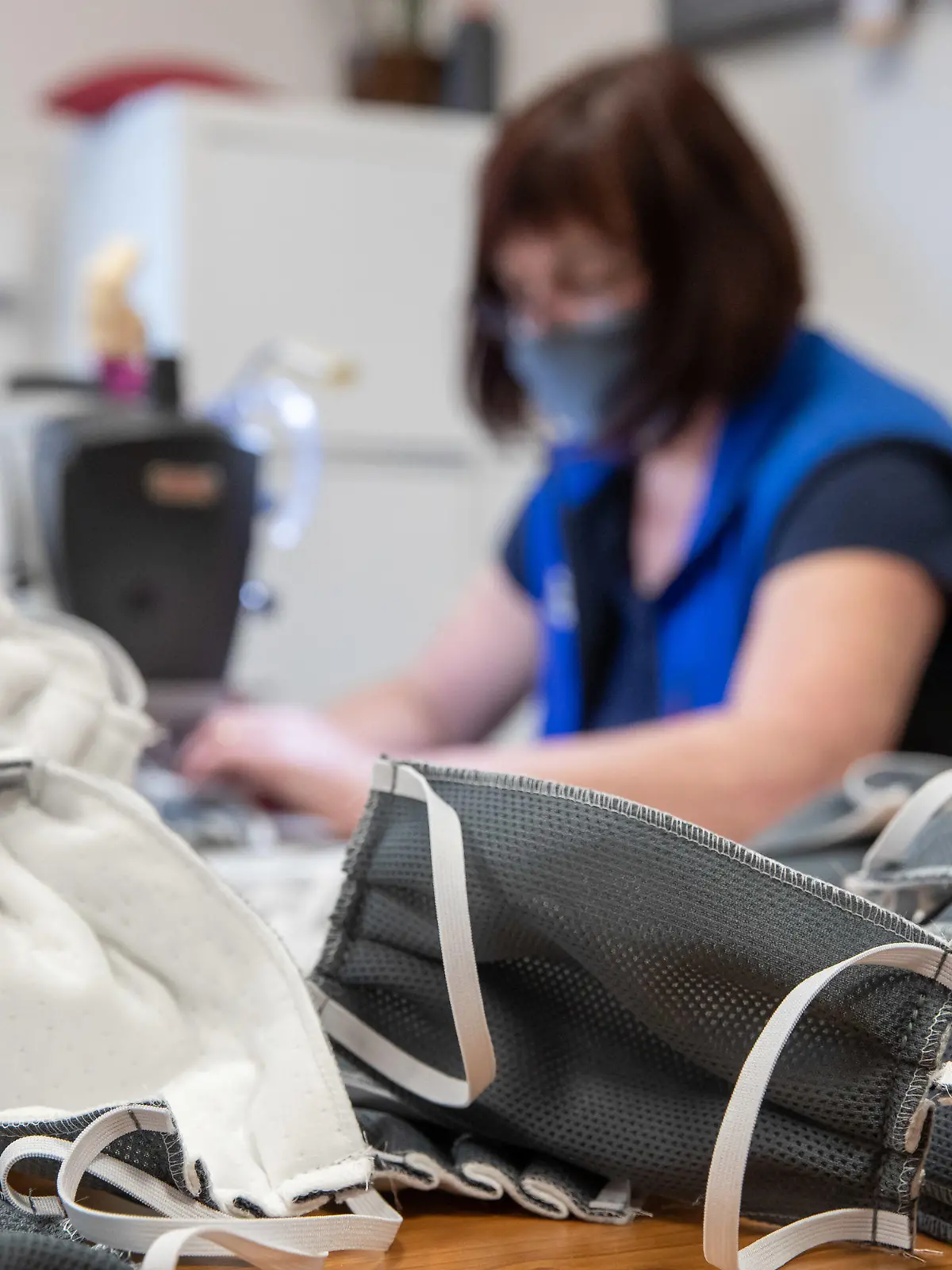 23.03.2020, Bayern, Würzburg: Eine Näherin des Matratzen- und Schaumstoff-Herstellers Wegerich, näht in der Produktion des Unternehmens Mundschutzmasken. Eigentlich produziert die Firma Matratzen für Wohnmobile und Pflegebetten. Als Verpackung verwendet sie einen speziellen Vlies, der rollenweise in dem Unternehmen herumliegt und aus dem auch OP-Masken bestehen. Zusammen mit einem Pflegedienst hat Wegerich eine Schutzmaske nach diesem Vorbild entwickelt. (zu dpa: Schutzmasken selbst gemacht: «Ein Zeichen der Solidarität») Foto: Daniel Karmann//dpa +++ dpa-Bildfunk +++