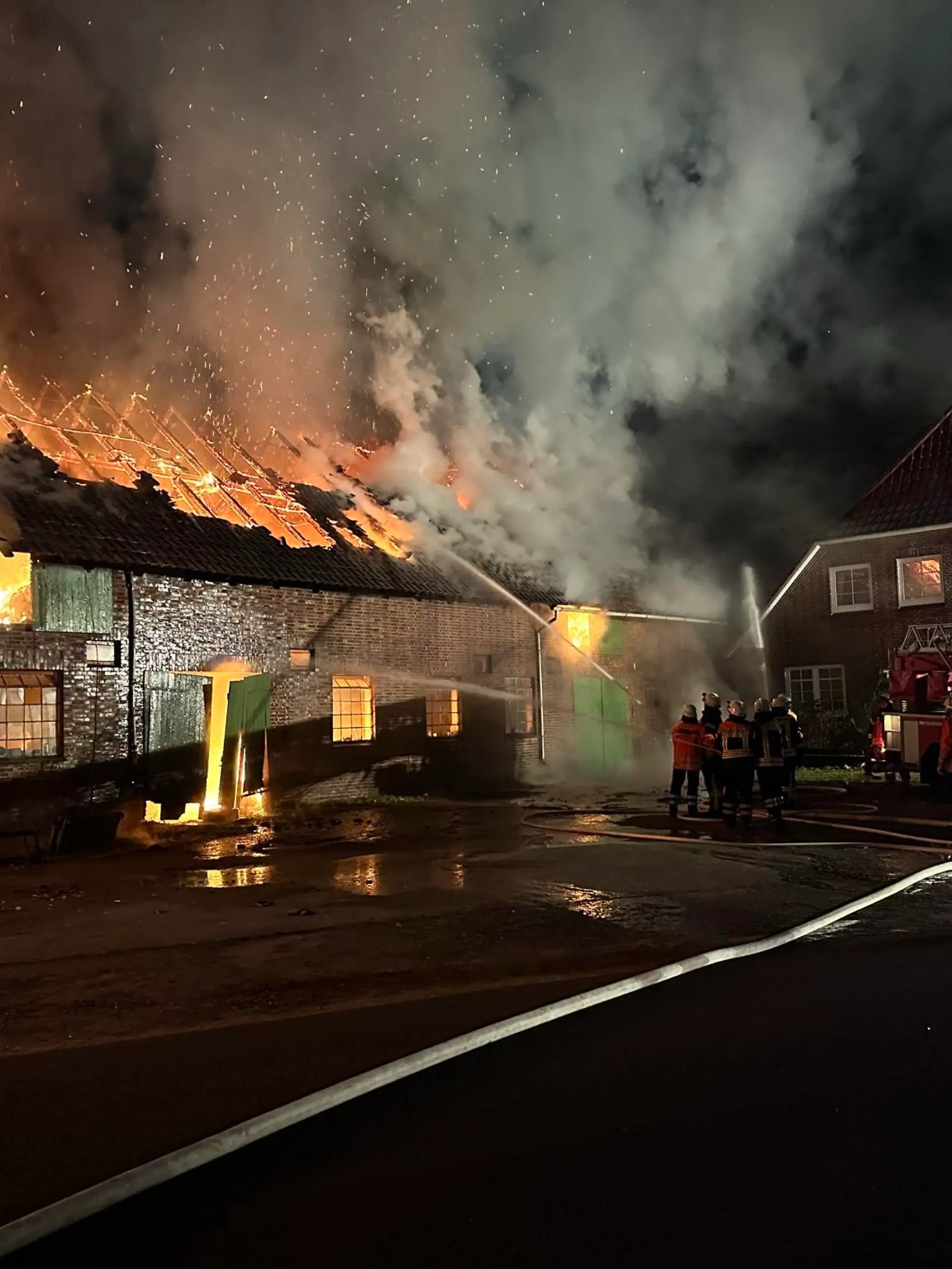 Blick auf die Scheune mit dem Wohnhaus im Hintergrund. Die Drehleiter aus Zeven wird gerade in Stellung gebracht