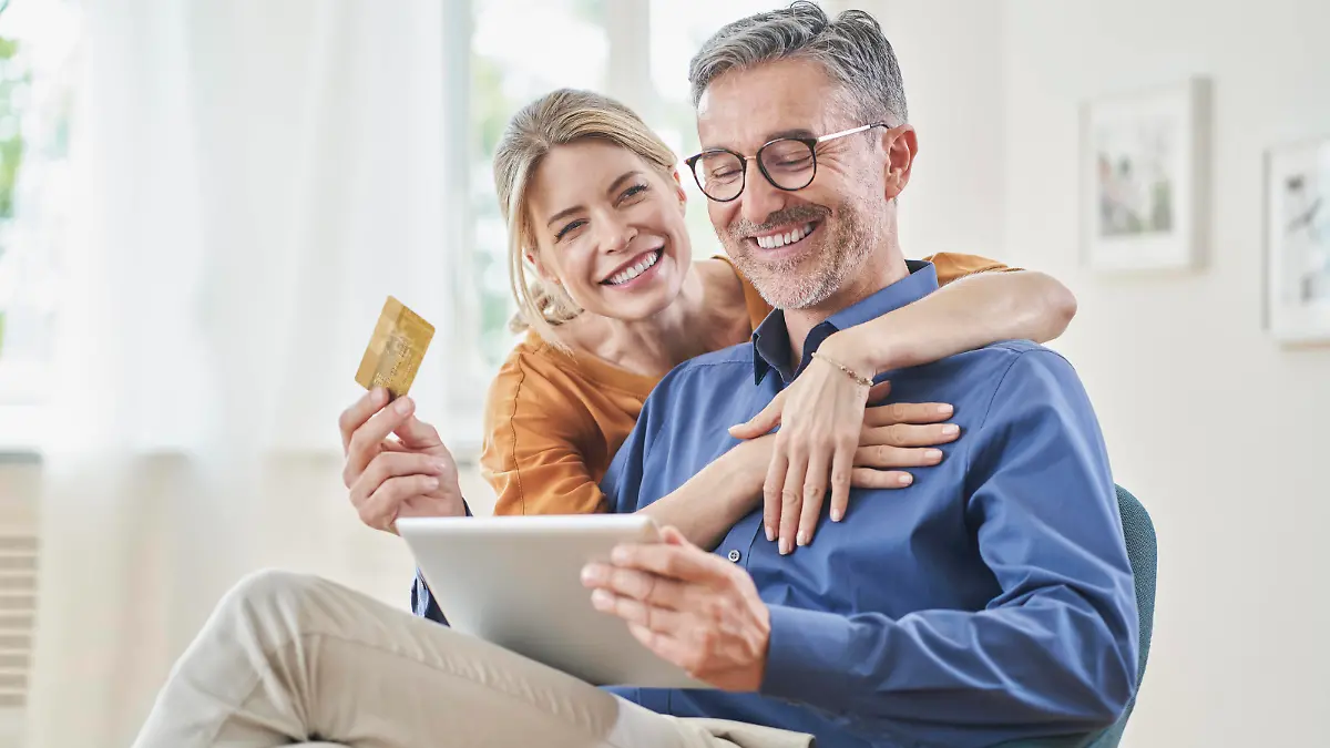 Happy woman embracing man with credit card doing online shopping through tablet PC at home model released, Symbolfoto property released, RORF03132