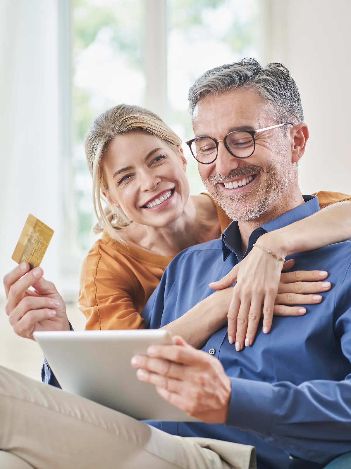 Happy woman embracing man with credit card doing online shopping through tablet PC at home model released, Symbolfoto property released, RORF03132