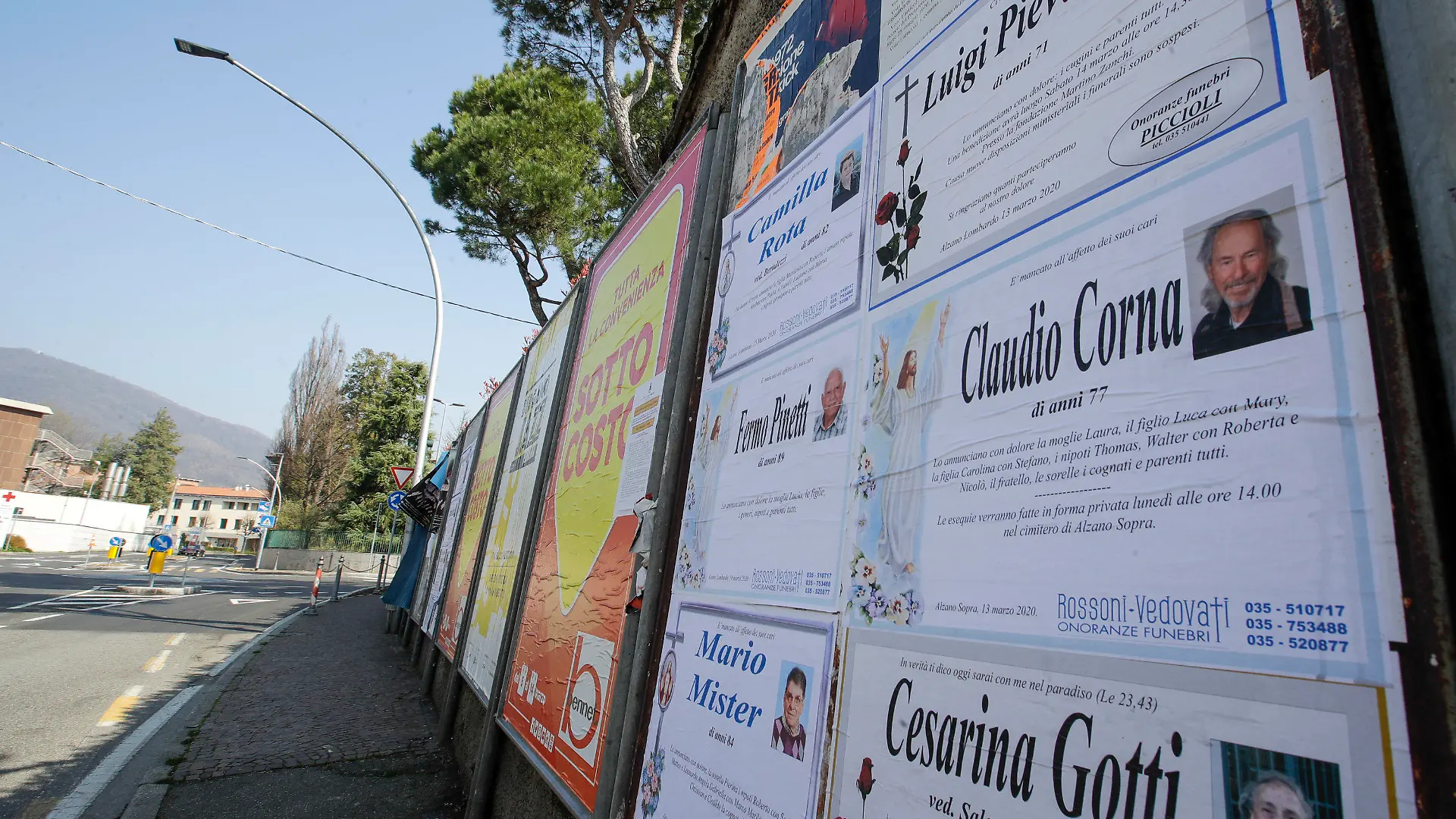 15.03.2020, Italien, Alzano Lombardo: Todesanzeigen sind auf einer Tafel entlang einer leeren Straße in Alzano Lombardo, in der Nähe von Bergamo zu sehen. In der Lombardei liegen die Metropole Mailand und die heftig von der Krankheit Covid-19 betroffene Zone um Bergamo. (zu dpa «Wo nur noch Totenglocken läuten») Foto: Luca Bruno/AP/dpa +++ dpa-Bildfunk +++