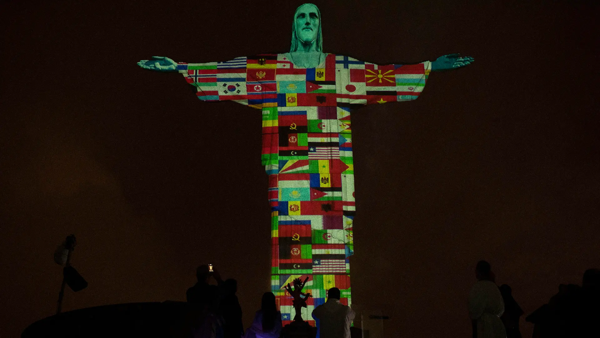 18.03.2020, Brasilien, Rio De Janeiro: Die Christusstatue (Cristo Redentor) ist mit Flaggen der Länder beleuchtet, die derzeit vom neuen Coronavirus befallen sind. Foto: Silvia Izquierdo/AP/dpa +++ dpa-Bildfunk +++