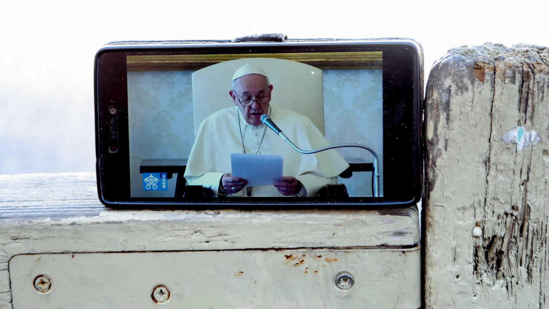 11.03.2020, Vatikan, Vatikanstadt: Die Übertragung der Generalaudienz von Papst Franziskus wird auf einem Handy abgespielt. Der Vatikan hat zum Schutz vor der Coronavirus-Welle am 10.03.2020 den Petersplatz für die Öffentlichkeit gesperrt. Foto: Evandro Inetti/ZUMA Wire/dpa +++ dpa-Bildfunk +++