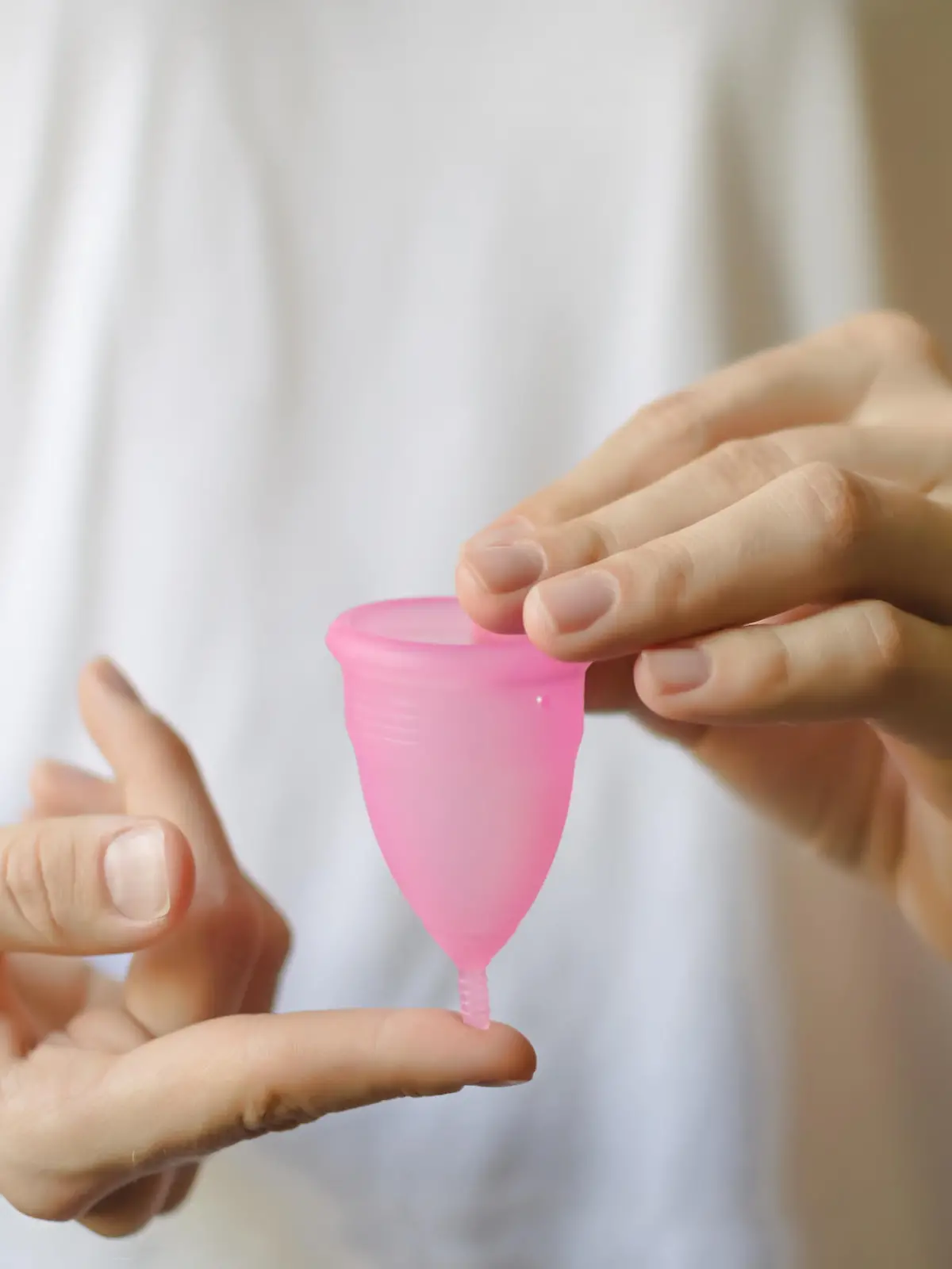 Frau hält Menstruationstasse in der Hand.