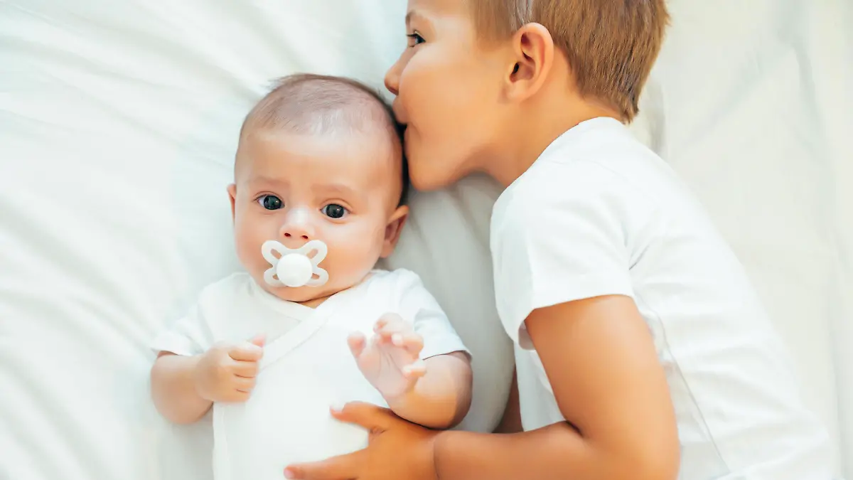 Older brother kissing baby boy in bed model released Symbolfoto PUBLICATIONxINxGERxSUIxAUTxHUNxONLY OCMF00632