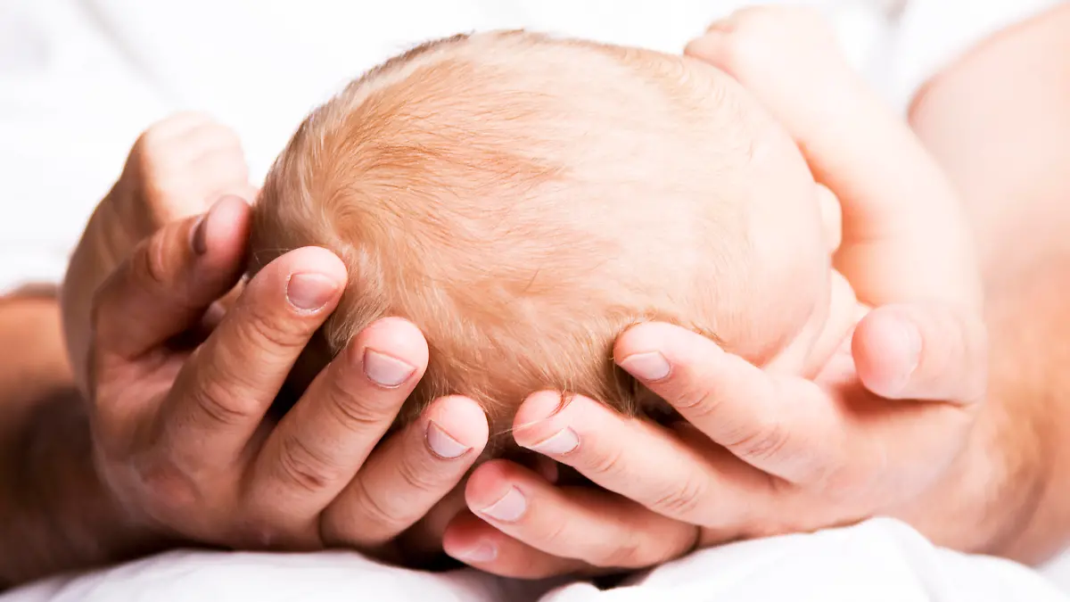 Vater hält Babykopf in den Händen