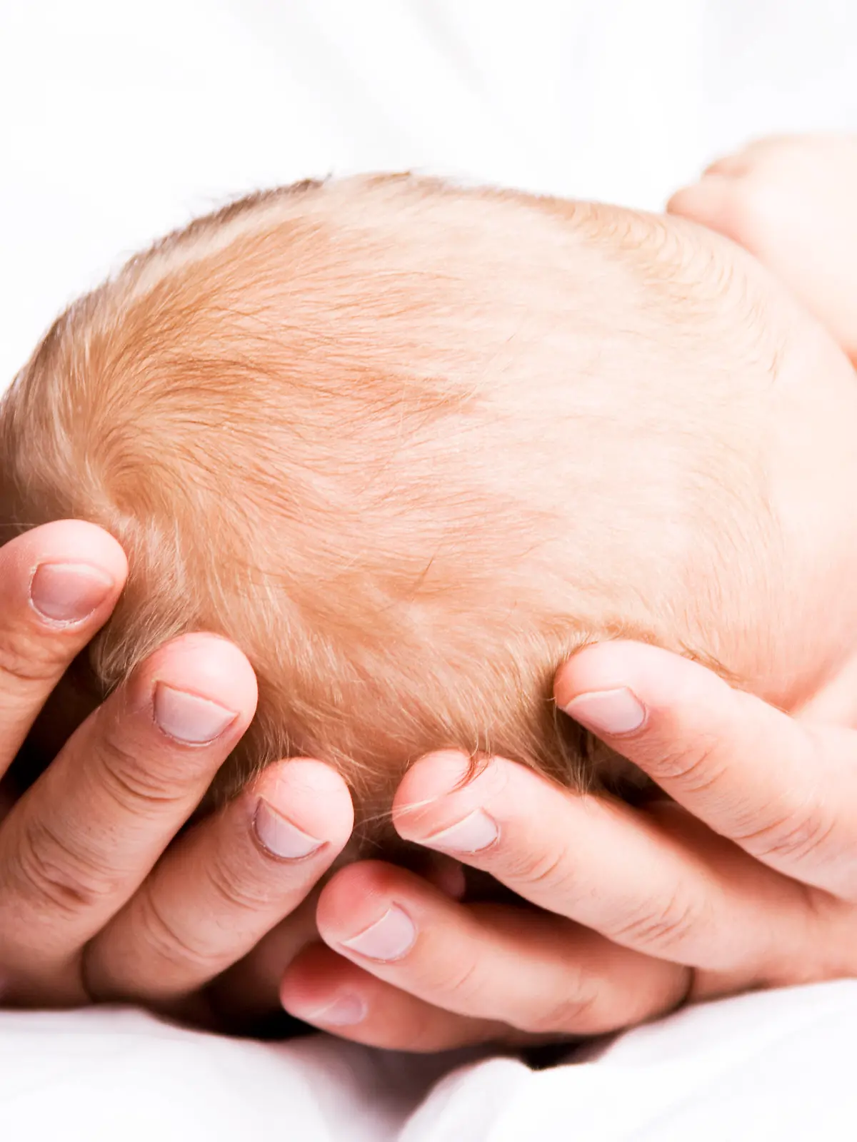 Vater hält Babykopf in den Händen
