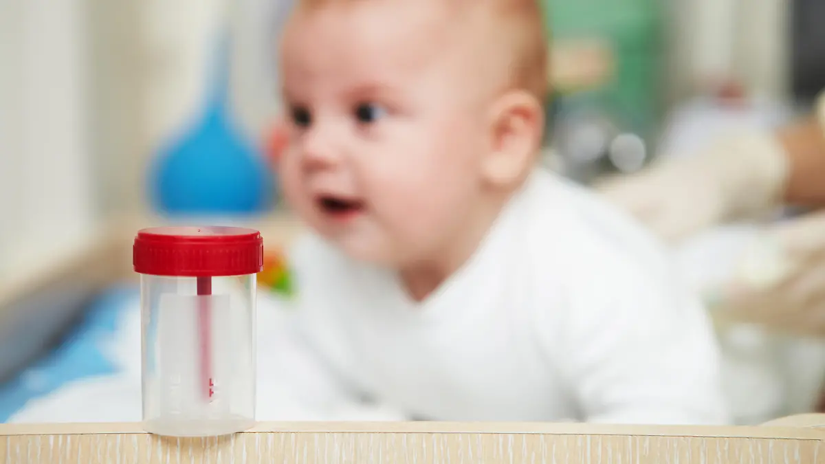 Urinprobe mit Baby im Hintergrund