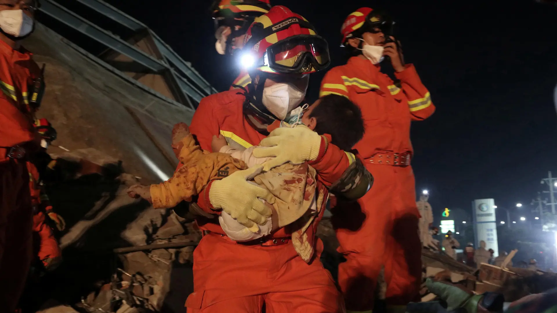A worker wearing a face mask rescues a child at the site where a hotel being used for the coronavirus quarantine collapsed, in the southeast Chinese port city of Quanzhou, Fujian province, China March 8, 2020. China Daily via REUTERS ATTENTION EDITORS - THIS IMAGE WAS PROVIDED BY A THIRD PARTY. CHINA OUT.