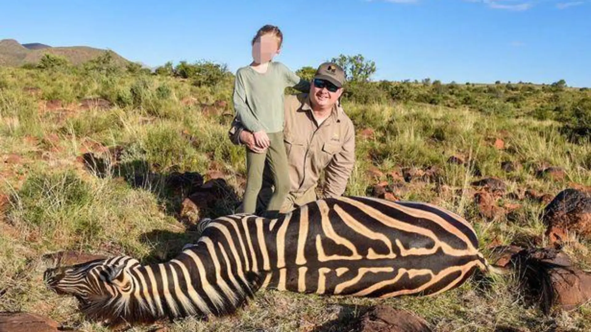 Ein neunjähriges Mädchen posiert neben einem toten Zebra.