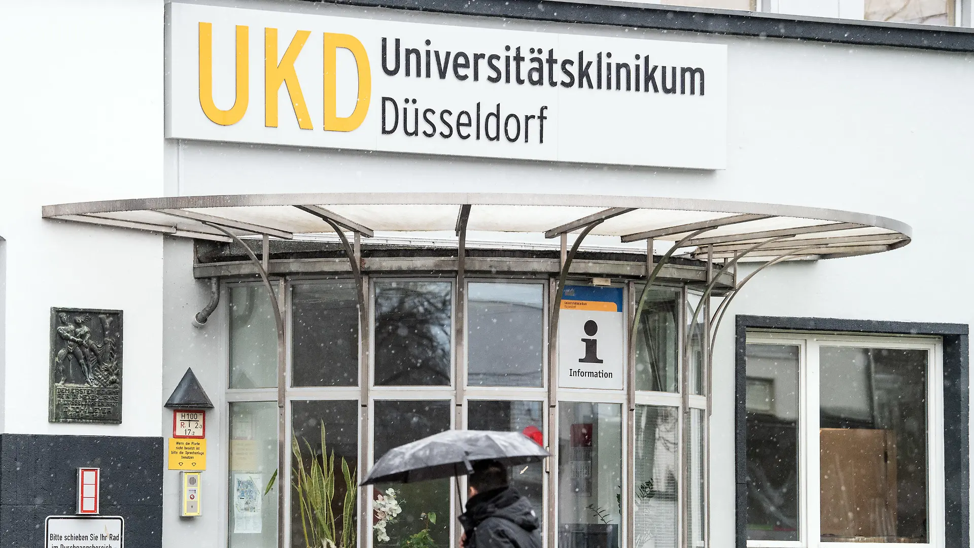 26.02.2020, Nordrhein-Westfalen, Düsseldorf: Ein Mann mit einem Regenschirm geht auf das Gelände des Universitätsklinikums Düsseldorf. Erstmals ist auch ein Patient in NRW nachweislich an dem neuartigen Coronavirus erkrankt und wird in der Universitätsklinik der Landeshauptstadt behandelt. Foto: Federico Gambarini/dpa +++ dpa-Bildfunk +++