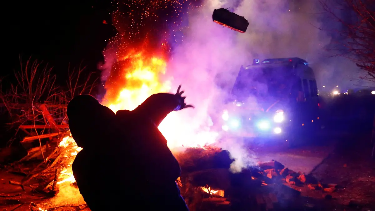 A demonstrator throws a stone towards a police van during a protest against the arrival of a plane carrying evacuees from coronavirus-hit China's Hubei province in the village of Novi Sanzhary in Poltava region, Ukraine February 20, 2020. Local residents blocked the road leading to a sanatorium where the evacuees are due to be held in quarantine for at least two weeks. REUTERS/Valentyn Ogirenko