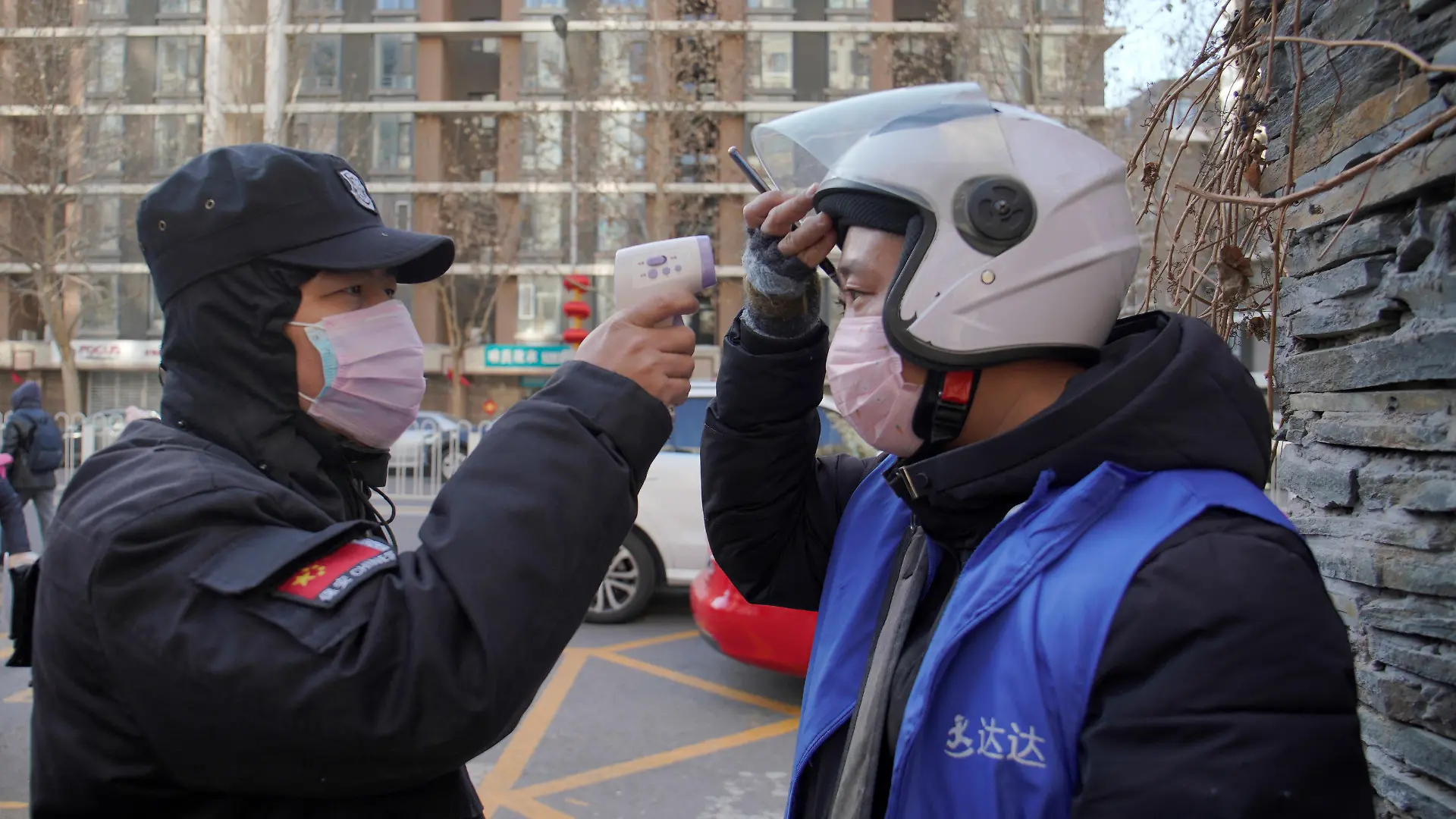 A security officer takes body temperature measurement of a delivery worker at a residential compound in Beijing, China as the country is hit by an outbreak of the new coronavirus, February 1, 2020. REUTERS/Stringer NO RESALES. NO ARCHIVES.