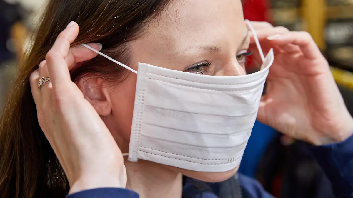 28.01.2020, Hamburg: Illustration - Eine Mitarbeiterin zieht sich in einem Fachgeschäft für Berufskleidung einen Mundschutz an.  Die Sorge vor Ansteckung mit dem neuartigen Coronavirus lässt in deutschen Apotheken die Nachfrage nach Atemmasken steigen. Ein Infektionsexperte hält dagegen Schutzmaßnahmen von Bürgern wie das Tragen von Mundschutz derzeit für unnötig. Foto: Georg Wendt/dpa +++ dpa-Bildfunk +++
