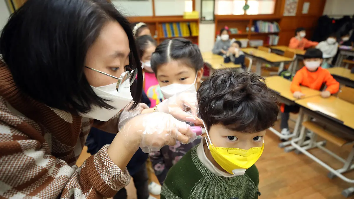 30.01.2020, Südkorea, Seoul: Eine Lehrerin misst am ersten Schultag nach den Winterferien die Temperaturen eines Grundschülers. Die Zahl der Infektionen und Todesopfer durch die Lungenkrankheit aus China ist erneut gestiegen. Foto: -/YNA/dpa +++ dpa-Bildfunk +++