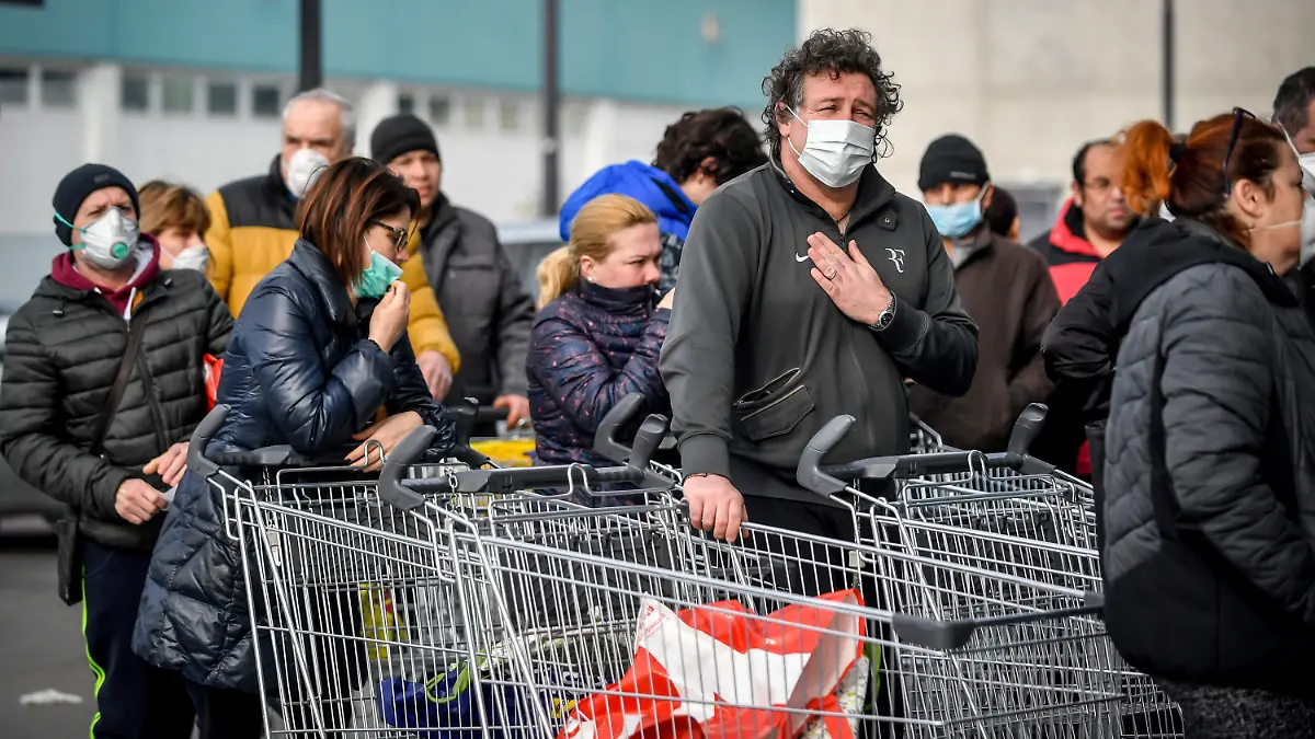 dpatopbilder - 23.02.2020, Italien, Casalpusterlengo: Menschen tragen Atemschutzmasken und stehen vor einem Supermarkt in einer Schlange. Nach dem Tod zweier Menschen sind Teile des öffentlichen Lebens zum Erliegen gekommen. Kein europäisches Land hat mehr Infektionen mit dem Virus Sars-CoV-2 registriert als Italien. Foto: Claudio Furlan/LaPresse/AP/dpa +++ dpa-Bildfunk +++