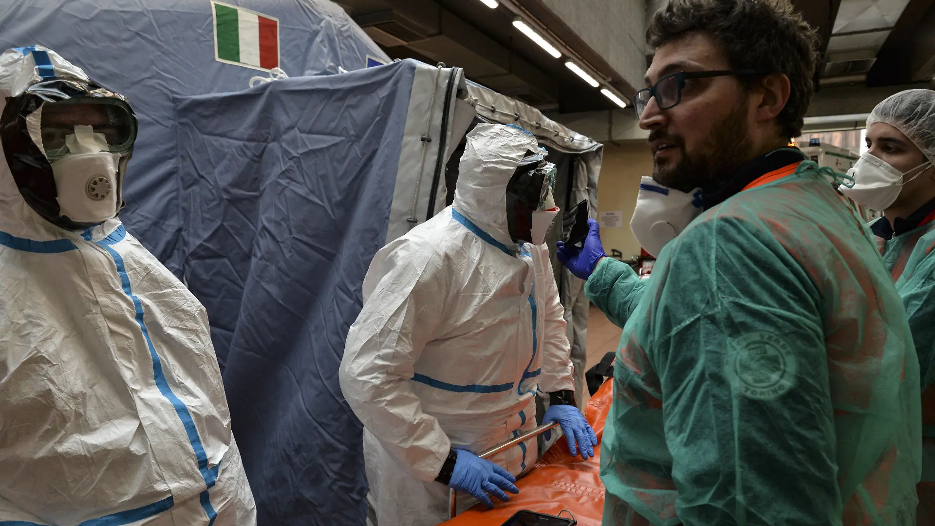 25.02.2020, Italien, Turin: Mitarbeiter in Schutzanzügen stehen in einem Krankenhaus neben einer Liege. Bei dem neuen Coronavirus steigt in Italien die Zahl der Toten und Infizierten weiter an. Foto: Diego Puletto/SOPA Images via ZUMA Wire/dpa +++ dpa-Bildfunk +++