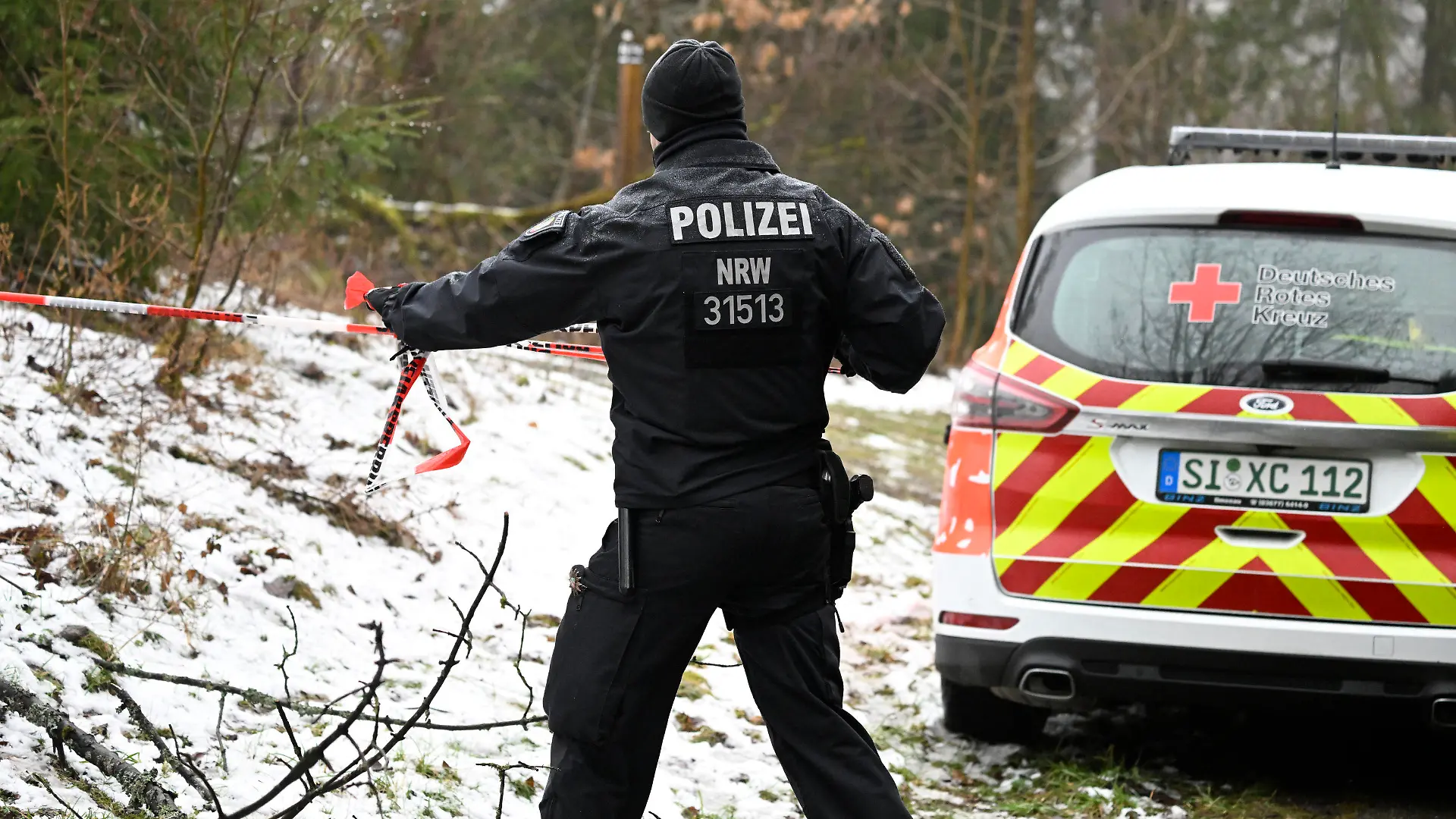 12.03.2023, Nordrhein-Westfalen, Freudenberg: Ein Polizist sperrt die Umgebung nahe des Fundorts einer Leiche weiträumig ab. Die seit Samstagabend vermisste Zwölfjährige aus dem südwestfälischen Freudenberg ist tot. Bei dem am Sonntagmittag gefundenen weiblichen Leichnam handele es sich um das gesuchte Mädchen, teilte die Polizei Koblenz am Abend mit. Foto: Roberto Pfeil/dpa +++ dpa-Bildfunk +++