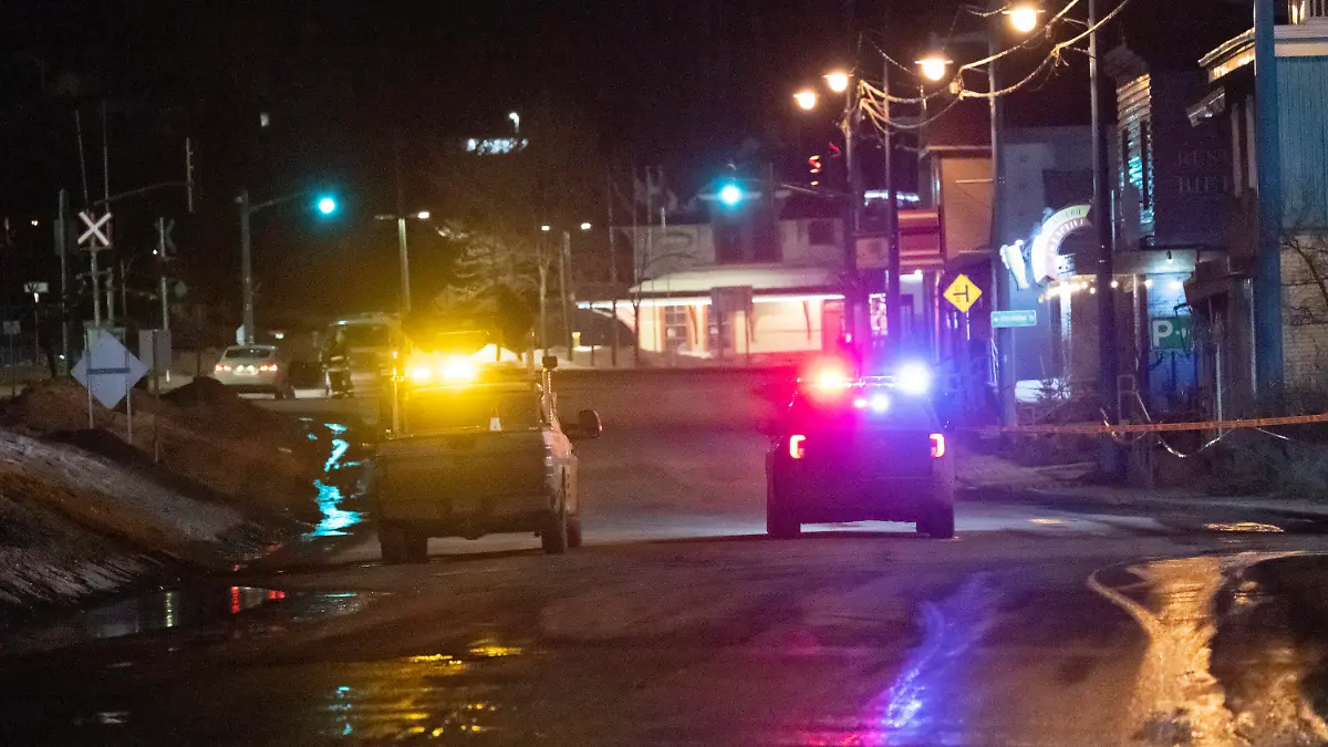 A police car and a Transport Quebec truck guard the perimeter of a fatal accident, in Amqui, Quebec, Monday, March 13, 2023. Two men died after a pickup truck plowed into pedestrians beside a road, although a senior Canadian official rapidly ruled out a terrorism attack or a national security incident. (Jacques Boissinot/The Canadian Press via AP)
