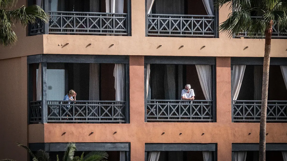 27.02.2020, Spanien, Santa Cruz de Tenerife: Das Hotel H10 Costa Adeje Palace, auf dessen Balkon Gäste stehen. Das wegen Coronavirus-Fällen unter Quarantäne gestellte Hotel auf Teneriffa ist weiterhin durch die Polizei abgeriegelt. Foto: Arturo Rodriguez/dpa +++ dpa-Bildfunk +++