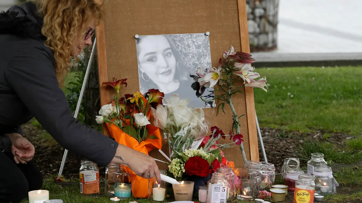 FILE - In this Dec. 12, 2018, file photo, a woman lights candles during a candlelight vigil for murdered British tourist Grace Millane at Cathedral Square in Christchurch, New Zealand. At a sentencing hearing at the Auckland High Court on Friday Feb. 21, 2020, the killer, who has name suppression, has been sentenced to life imprisonment with a minimum non-parole period of 17 years. (AP Photo/Mark Baker, File)