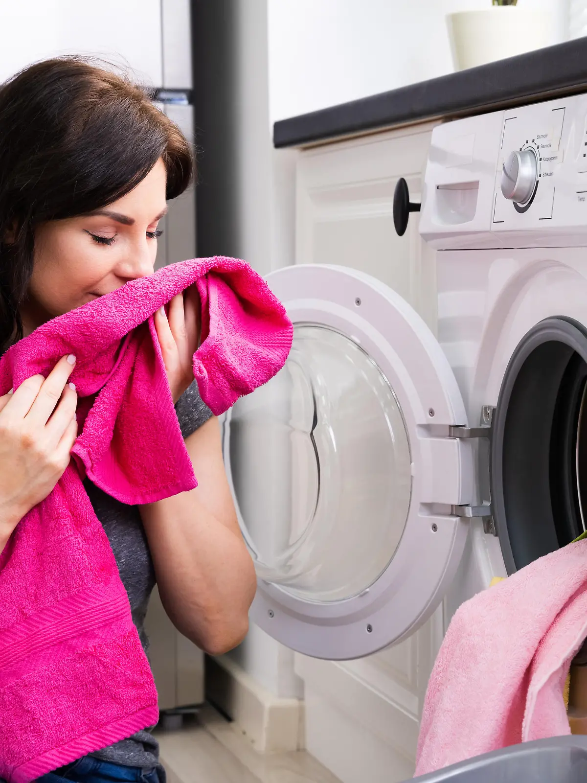 Woman Smelling Clothes At Home Doing Laundry