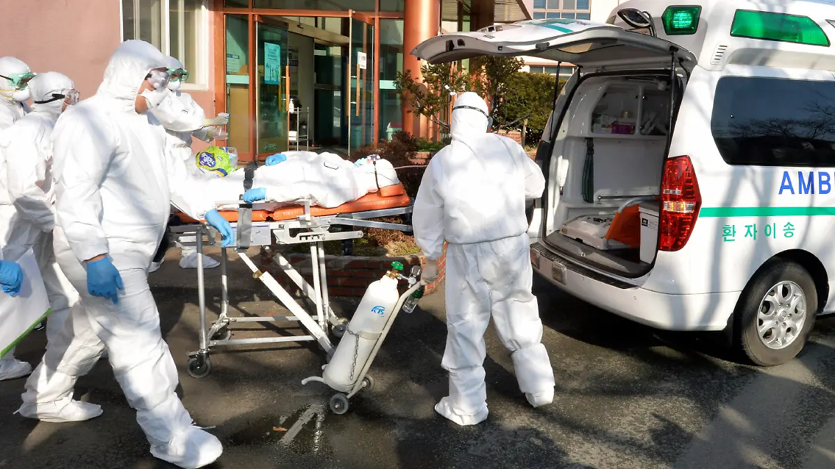Medial workers wearing protective gears carry a patient suspected of contracting the new coronavirus toward an ambulance at Daenam Hospital in Cheongdo, South Korea, Friday, Feb. 21, 2020. South Korea reported 100 new virus cases Friday, bringing the country's total to 204, many of them clustered around a southeastern city, and raising fears that the outbreak is getting out of control. (Lee Moo-ryul/Newsis via AP)