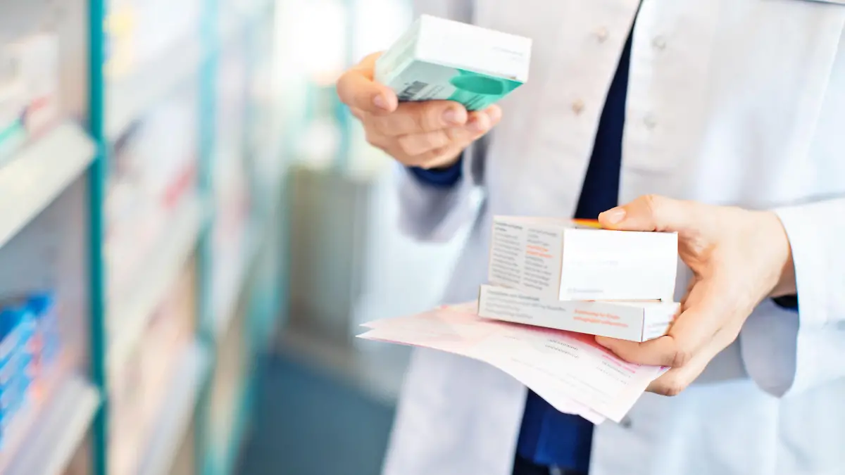 Closeup of pharmacist's hands taking medicines from shelf at the pharmacy