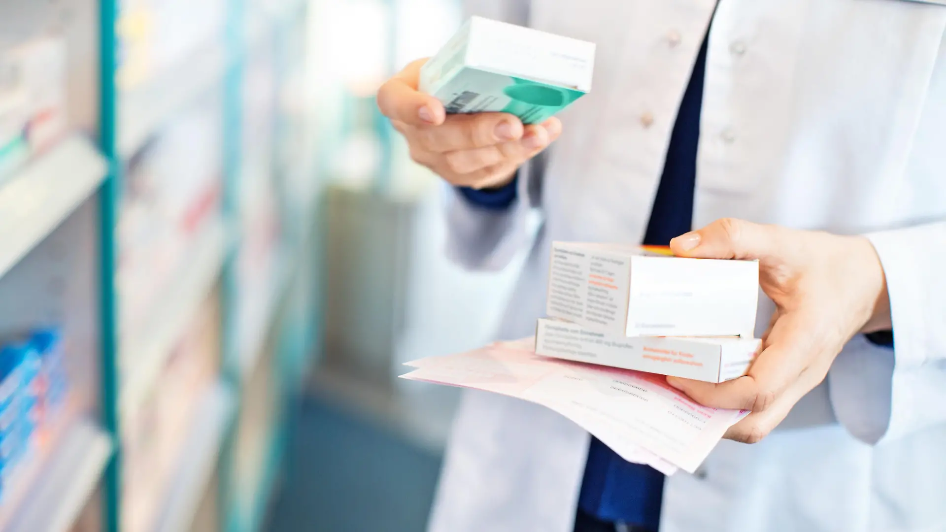 Closeup of pharmacist's hands taking medicines from shelf at the pharmacy