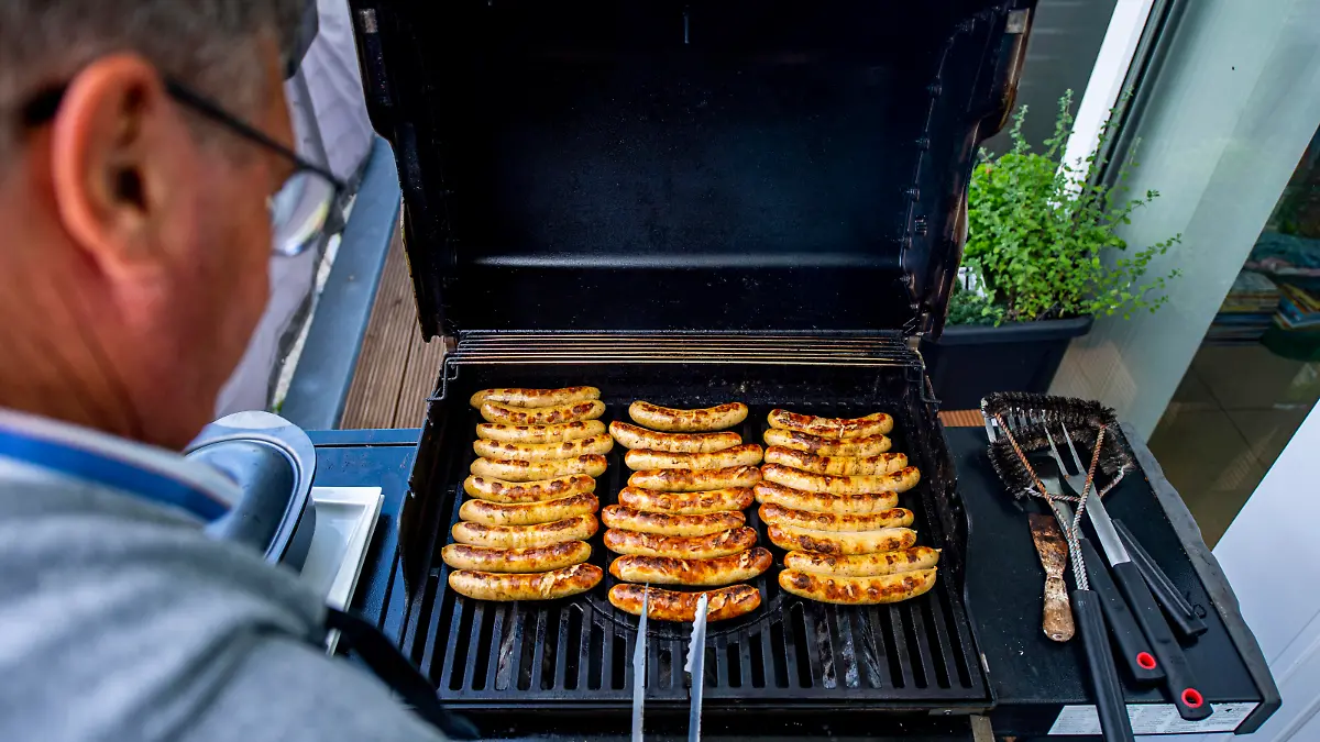 Ein Mann wendet Würstchen auf einem Grill. Das frühlingshafte Wetter lädt zum Angrillen in diesem Frühjahr und zu dieser Grillsaison ein. Foto: Inderlied/Kirchner-Media