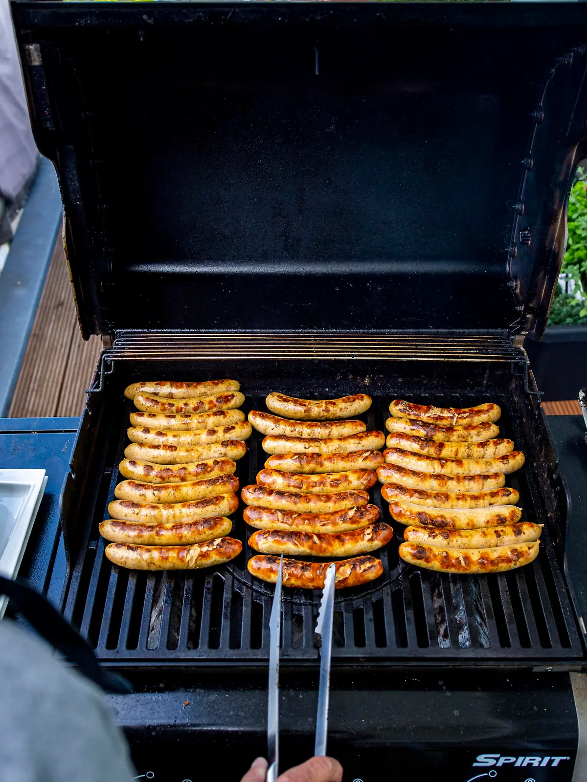 Ein Mann wendet Würstchen auf einem Grill. Das frühlingshafte Wetter lädt zum Angrillen in diesem Frühjahr und zu dieser Grillsaison ein. Foto: Inderlied/Kirchner-Media