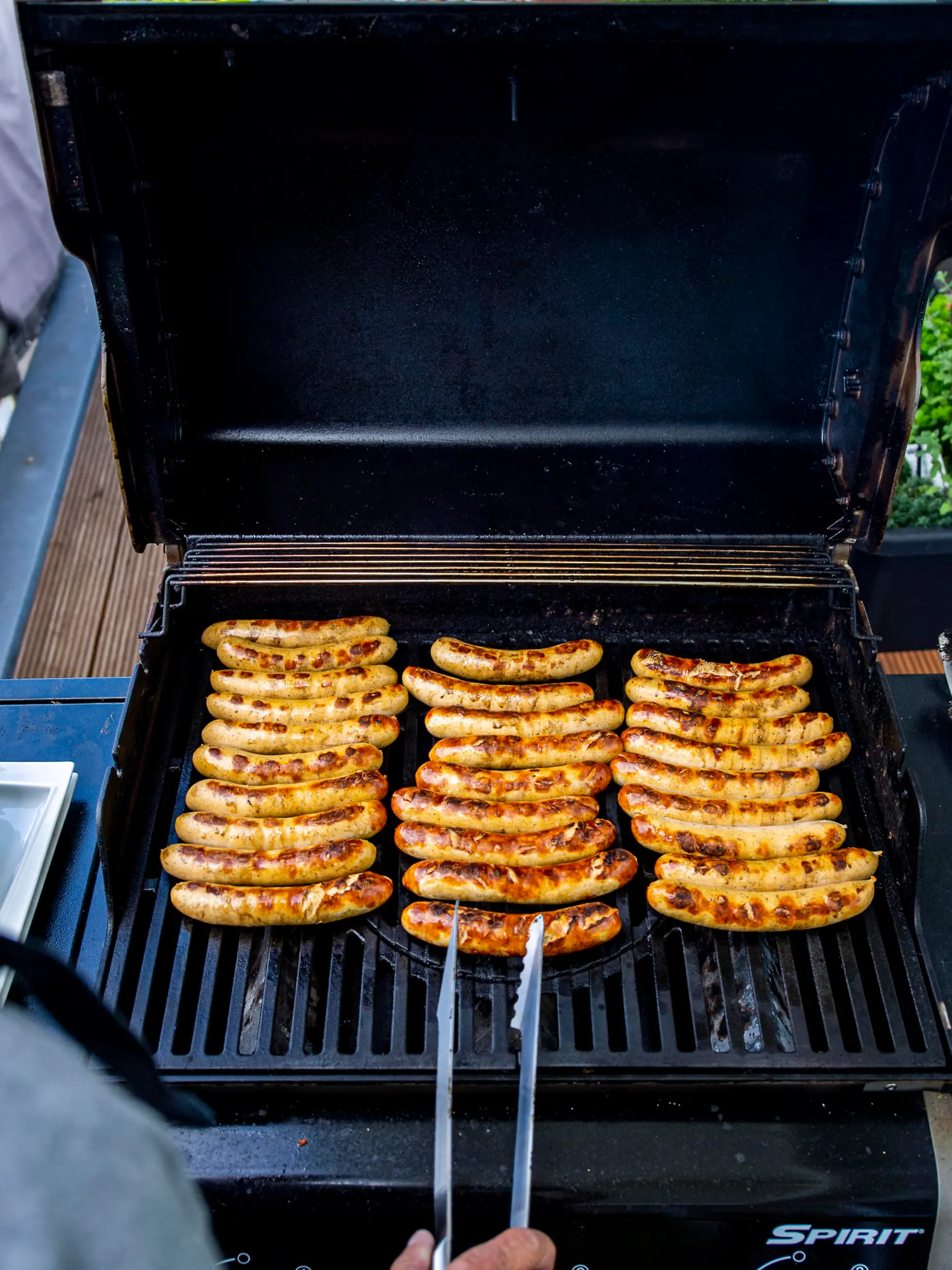 Ein Mann wendet Würstchen auf einem Grill. Das frühlingshafte Wetter lädt zum Angrillen in diesem Frühjahr und zu dieser Grillsaison ein. Foto: Inderlied/Kirchner-Media