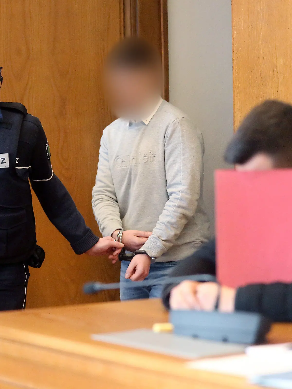 17.02.2020, Nordrhein-Westfalen, Kleve: Der Hauptangeklagte (2.v.l) wird von einem Justizbeamten am Mitangeklagten (r) vorbei zur Anklagebank gebracht. Den Angeklagten wird vorgeworfen, ein verbotenes Autorennen in Moers veranstaltet zu haben. Einer der beiden stieß mit dem Wagen einer unbeteiligten Frau zusammen, die drei Tage später starb. Foto: Roland Weihrauch/dpa - ACHTUNG: Angeklagter auf Anweisung des Gerichts gepixelt +++ dpa-Bildfunk +++