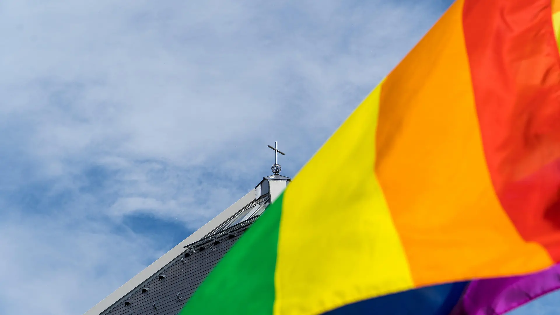 ARCHIV - 09.05.2021, Baden-Württemberg, Baden-Baden: Eine Regenbogenfahne weht vor der Autobahnkirche St. Christophorus am Rande der Segnung von gleichgeschlechtlichen Paaren. Ab März 2026 wird es in der katholischen Kirche in Deutschland offizielle Segensfeiern für homosexuelle Paare geben. Das hat die Synodalversammlung zur Reform der katholischen Kirche am Freitag in Frankfurt/Main beschlossen. Foto: Benedikt Spether/dpa +++ dpa-Bildfunk +++