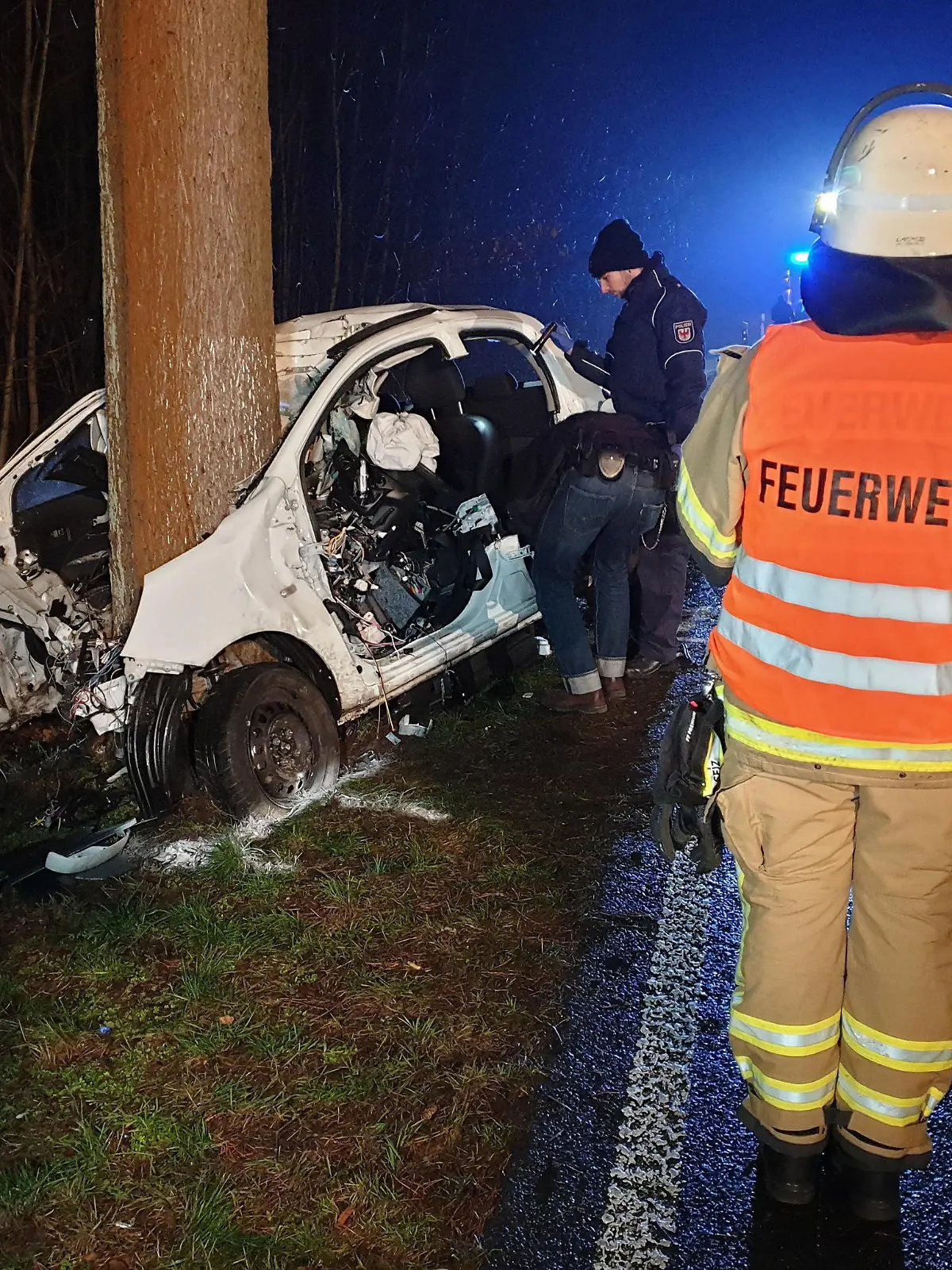 14.02.2020, Brandenburg, Baruth: Zwei Polizisten und ein Feuerwehrmann stehen neben einem stark beschädigten Auto. Eine 22 Jahre alte Autofahrerin ist bei einem Unfall im Landkreis Teltow-Fläming ums Leben gekommen. Foto: Julian Stähle/dpa-Zentralbild/dpa +++ dpa-Bildfunk +++