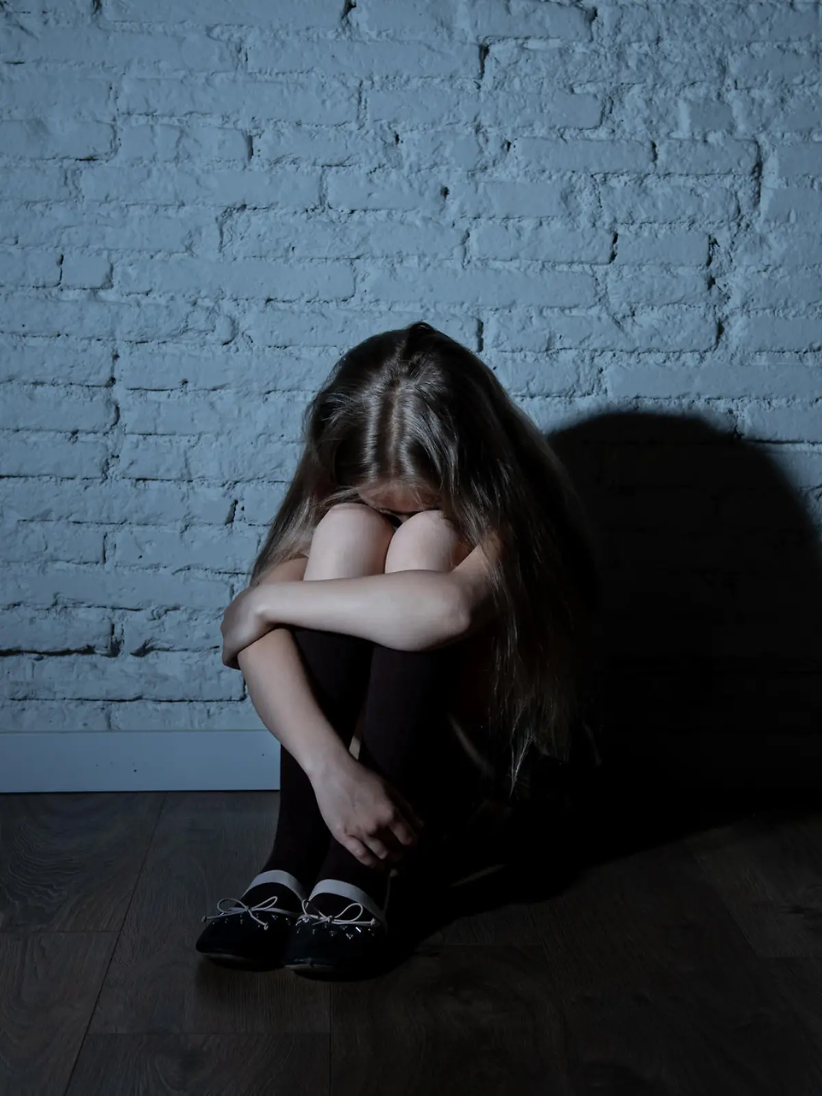 Mädchen kauert im Schulflur und hat Angst vor der Schule