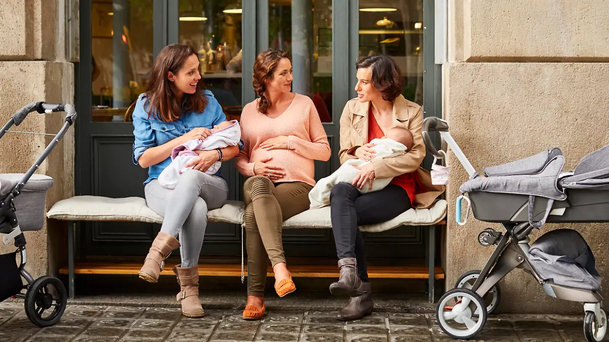 Drei junge Mütter mit Kinderwagen unterhalten sich