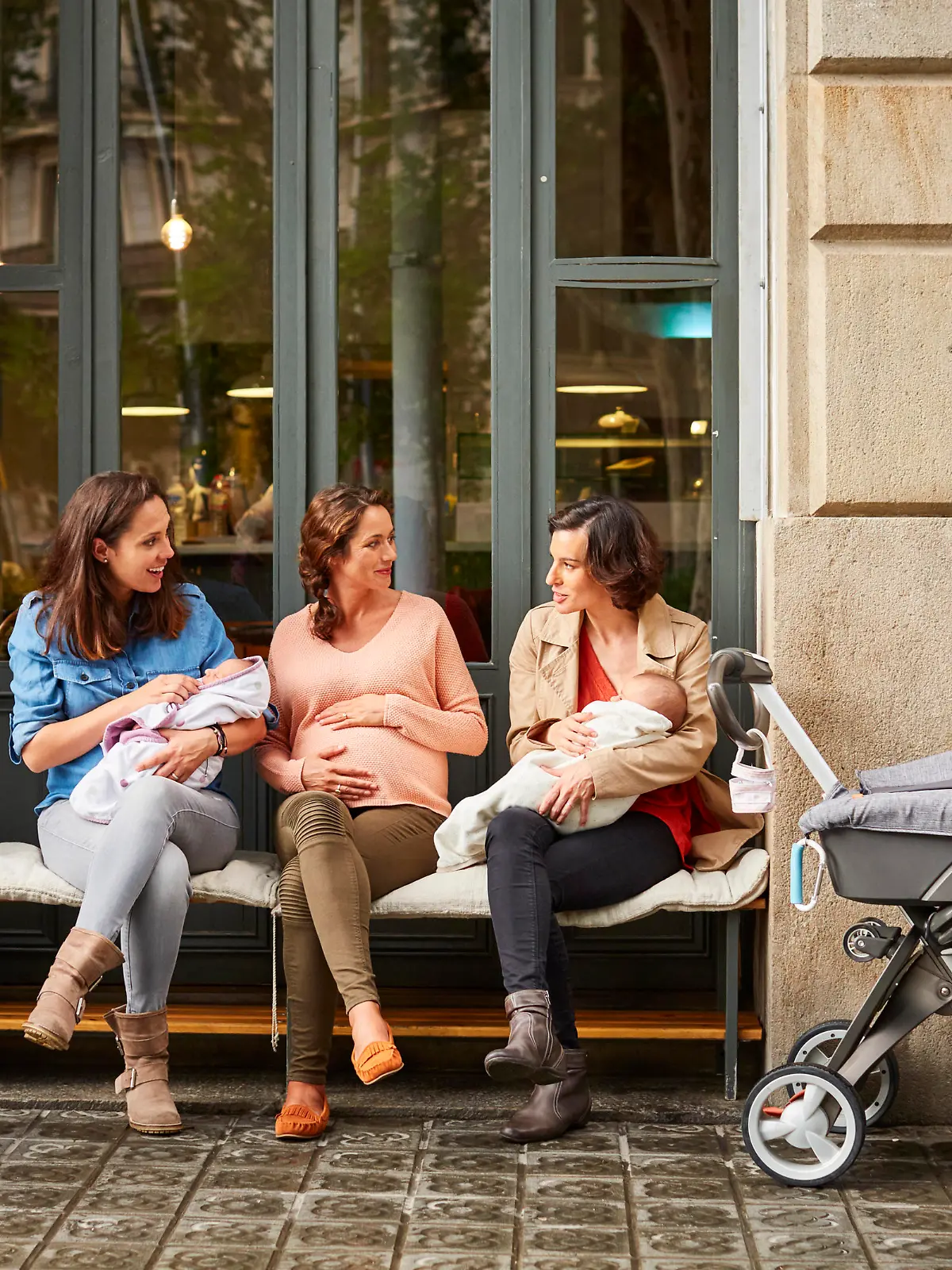 Drei junge Mütter mit Kinderwagen unterhalten sich