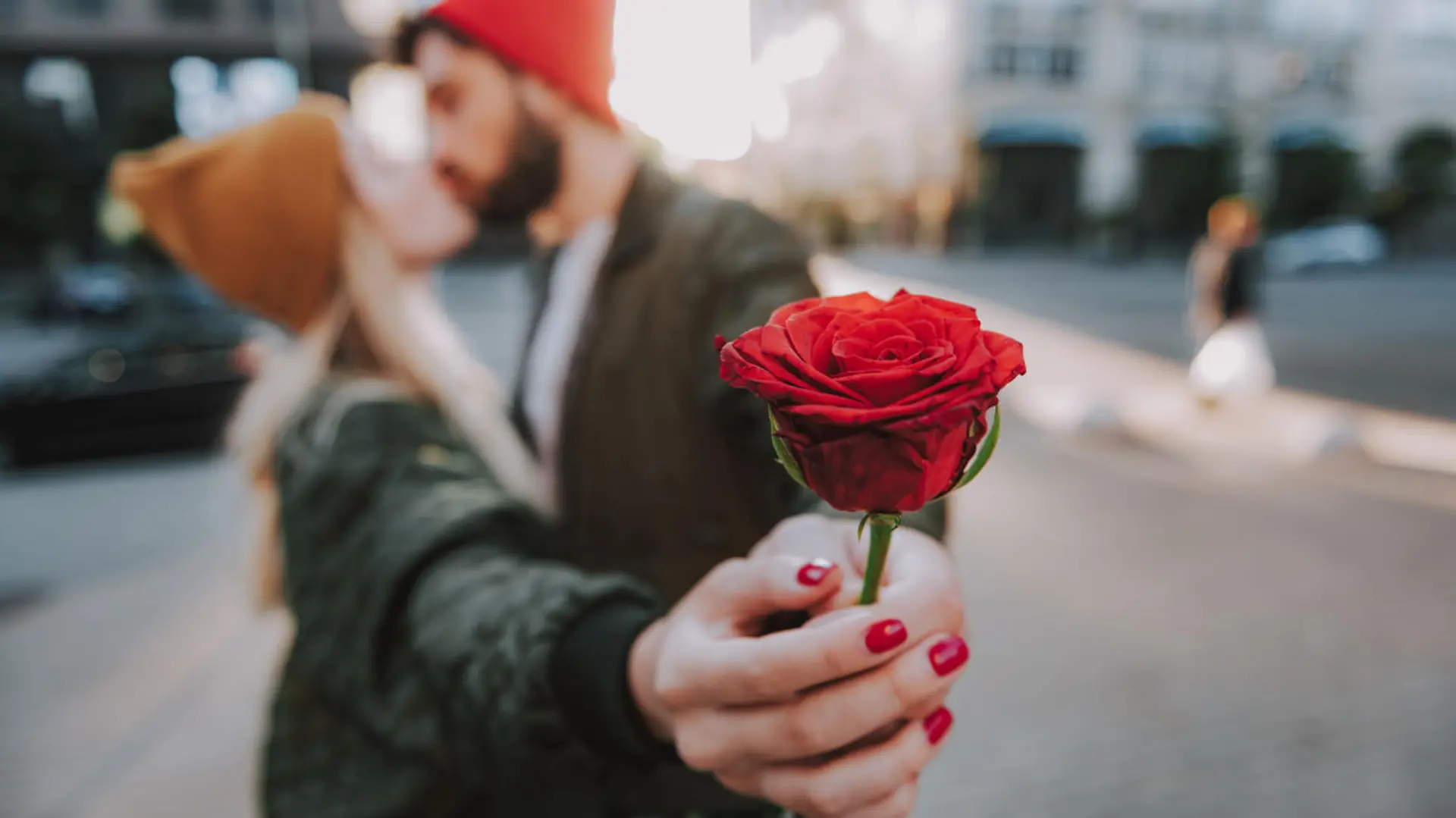 Mann küsst Frau und schenkt ihr Rose