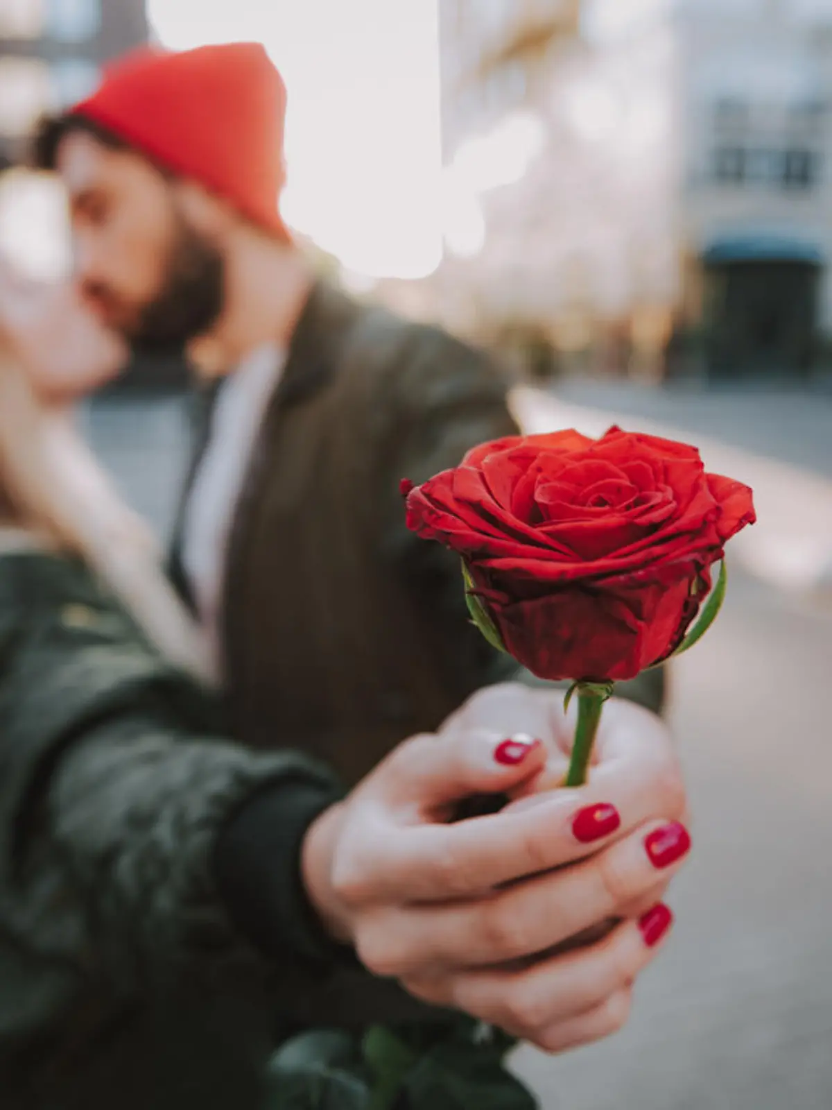 Mann küsst Frau und schenkt ihr Rose