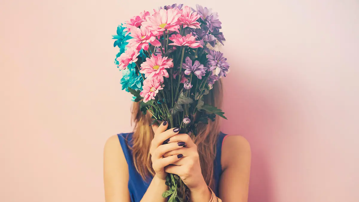 Young attractive beautiful woman smelling flowers.