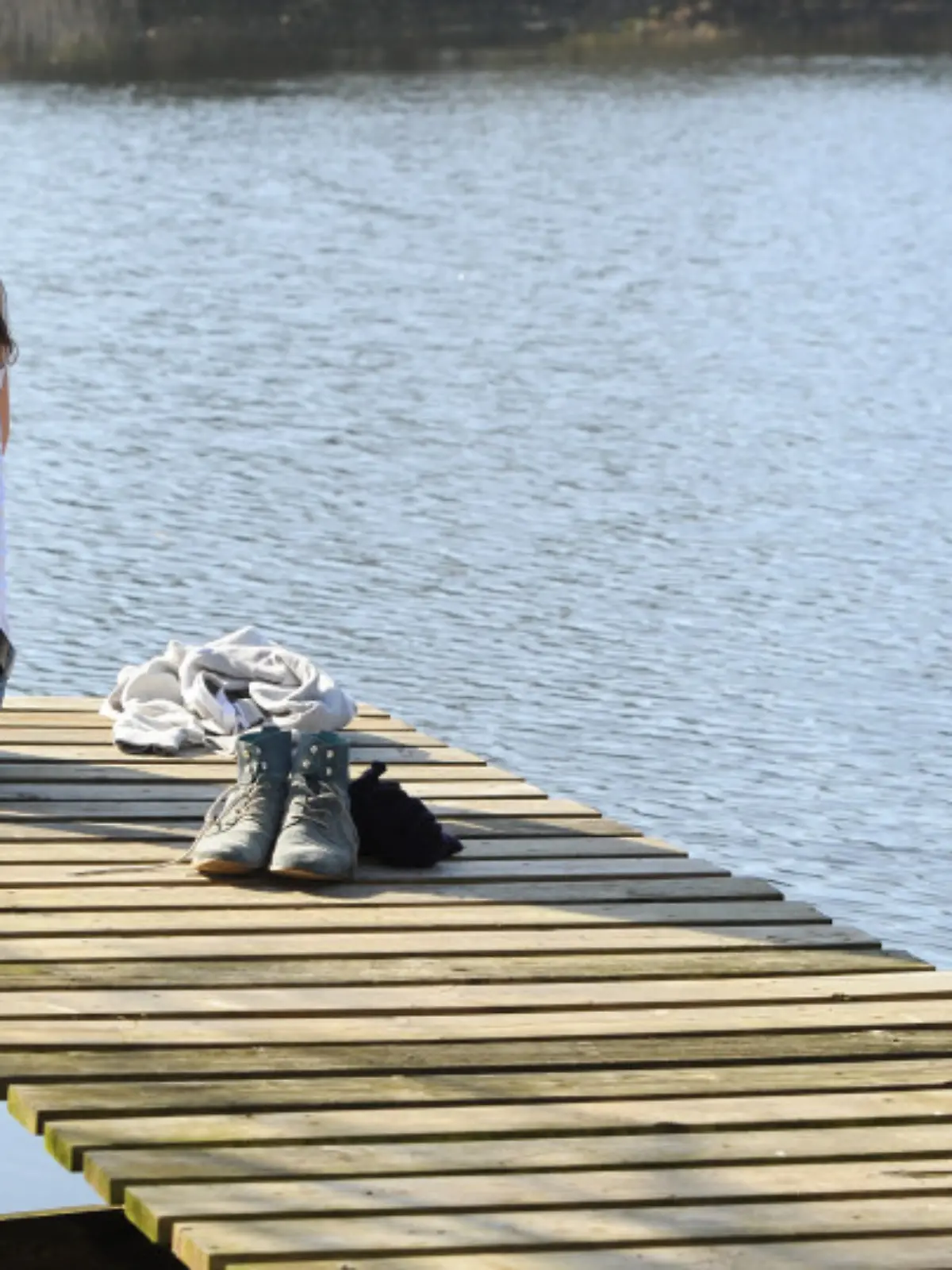 Eine junge Frau sitzt am 09.03.2014 bei frühlingshaftem Wetter auf einem Steg am Fährhofsee in Sottrum (Niedersachsen). Foto: Ingo Wagner/dpa +++(c) dpa - Bildfunk+++