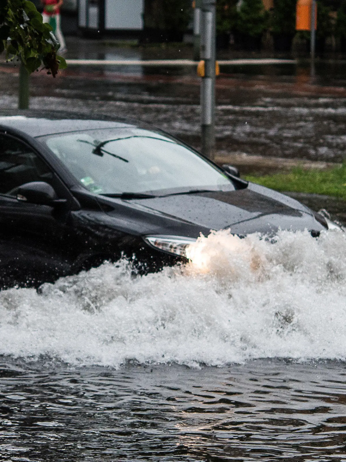 dpatopbilder - Ein Pkw fährt am 22.07.2017 in Berlin nach einem Gewitter und starken Regenfällen durch die Wassermassen in der Breiten Straße. Foto: Paul Zinken/dpa +++(c) dpa - Bildfunk+++
