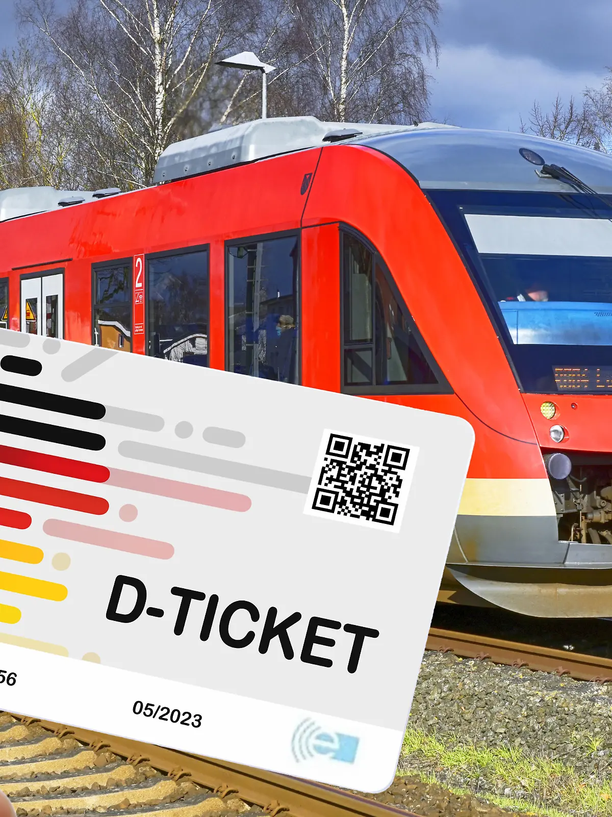 Hand hält das Deutschlandticket D-Ticket vor einer Regionalbahn / action press