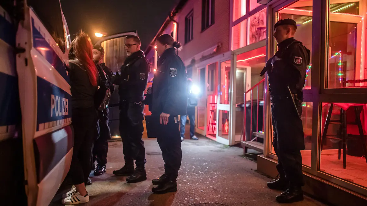 31.01.2020, Nordrhein-Westfalen, Essen: Polizisten nehmen während einer gemeinsamen Razzia von Ordnungsamt, Polizei, Ausländerbehörde und Steuerfahndung im Rotlichtviertel an der Stahlstraße die Personalien einer jungen Frau auf. Bei einer behördenübergreifenden Razzia im Essener Rotlichtviertel sind am Freitagabend den 31.01.2020 Bordelle und mehrere Dutzend Prostituierte kontrolliert worden. Überprüft wurde unter anderem, ob die Frauen ordnungsgemäß angemeldet sind und sich regelmäßig gesundheitlich untersuchen lassen. Foto: Bernd Thissen/dpa +++ dpa-Bildfunk +++