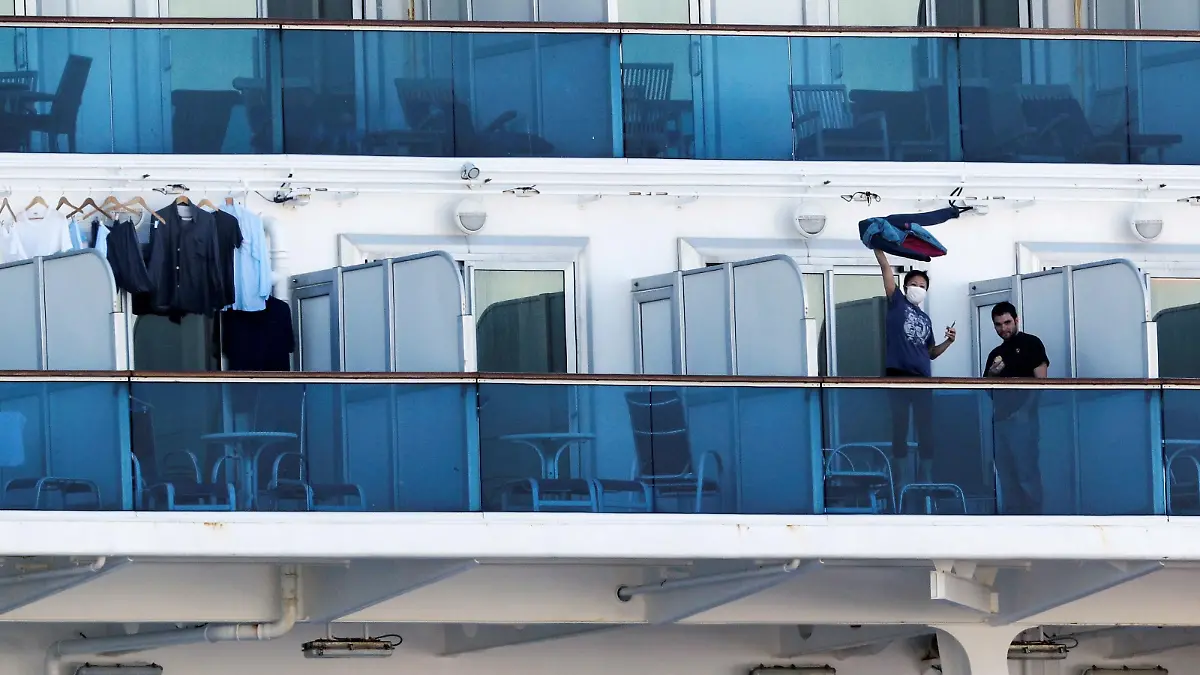 A passenger waves a jacket towards a woman (not pictured) on land as they communicate via phone at the balcony of a cabin on the cruise ship Diamond Princess, as the vessel's passengers continue to be tested for coronavirus, at Daikoku Pier Cruise Terminal in Yokohama, south of Tokyo, Japan February 13, 2020. REUTERS/Kim Kyung-Hoon
