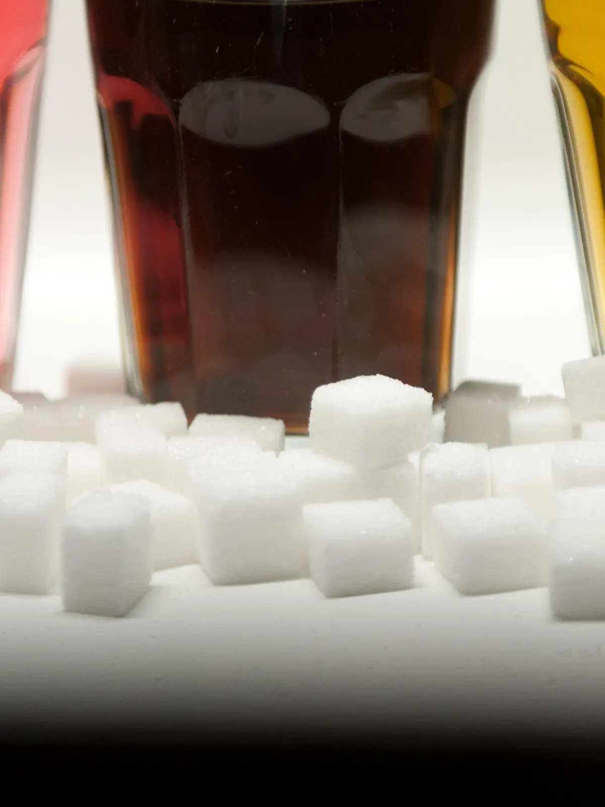 ARCHIV - ILLUSTRATION - Drei Gläser gefüllt mit roter Limonade, Cola und Energy-Drink stehen am 23.08.2016 in Berlin neben Zuckerwürfeln auf einem Tisch. Zucker hat viele Namen: Glukosesirup, Fruktose, Maltose oder Saccharose zum Beispiel. Klingt ungesund - aber ist es das auch? Ein Ernährungstrend dreht sich um die Abstinenz von dem «süßen Gift». (zu dpa "Vegan war gestern: Was steckt hinter dem Ernährungstrend Zuckerfrei?" vom 15.05.2017) Foto: Monika Skolimowska/dpa +++(c) dpa - Bildfunk+++