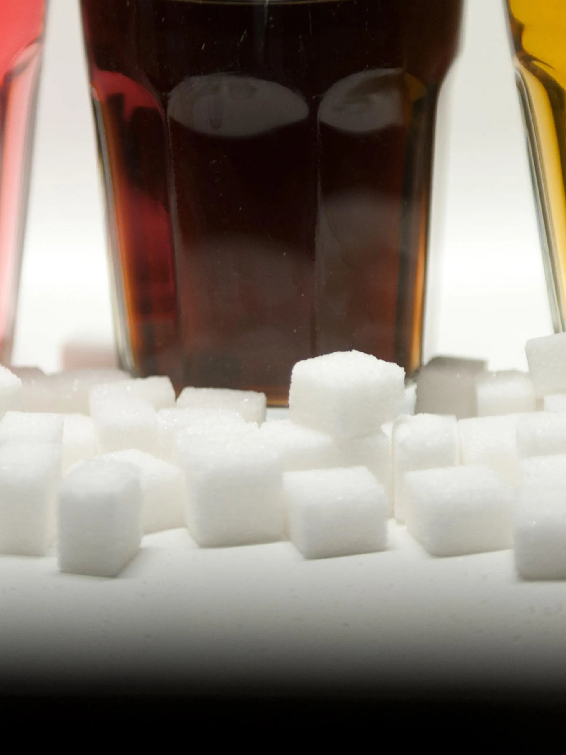 ARCHIV - ILLUSTRATION - Drei Gläser gefüllt mit roter Limonade, Cola und Energy-Drink stehen am 23.08.2016 in Berlin neben Zuckerwürfeln auf einem Tisch. Zucker hat viele Namen: Glukosesirup, Fruktose, Maltose oder Saccharose zum Beispiel. Klingt ungesund - aber ist es das auch? Ein Ernährungstrend dreht sich um die Abstinenz von dem «süßen Gift». (zu dpa "Vegan war gestern: Was steckt hinter dem Ernährungstrend Zuckerfrei?" vom 15.05.2017) Foto: Monika Skolimowska/dpa +++(c) dpa - Bildfunk+++