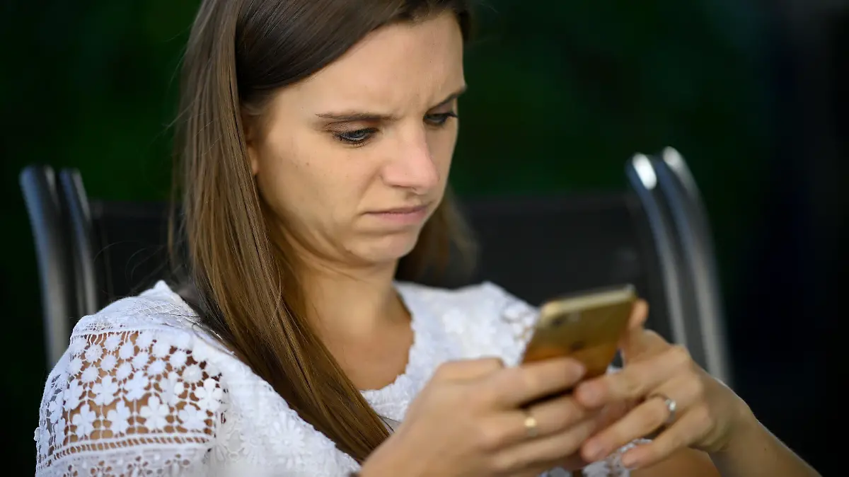 Junge Frau, mit Smartphone, skeptisch, Stuttgart, Baden-Württemberg, Deutschland | Verwendung weltweit