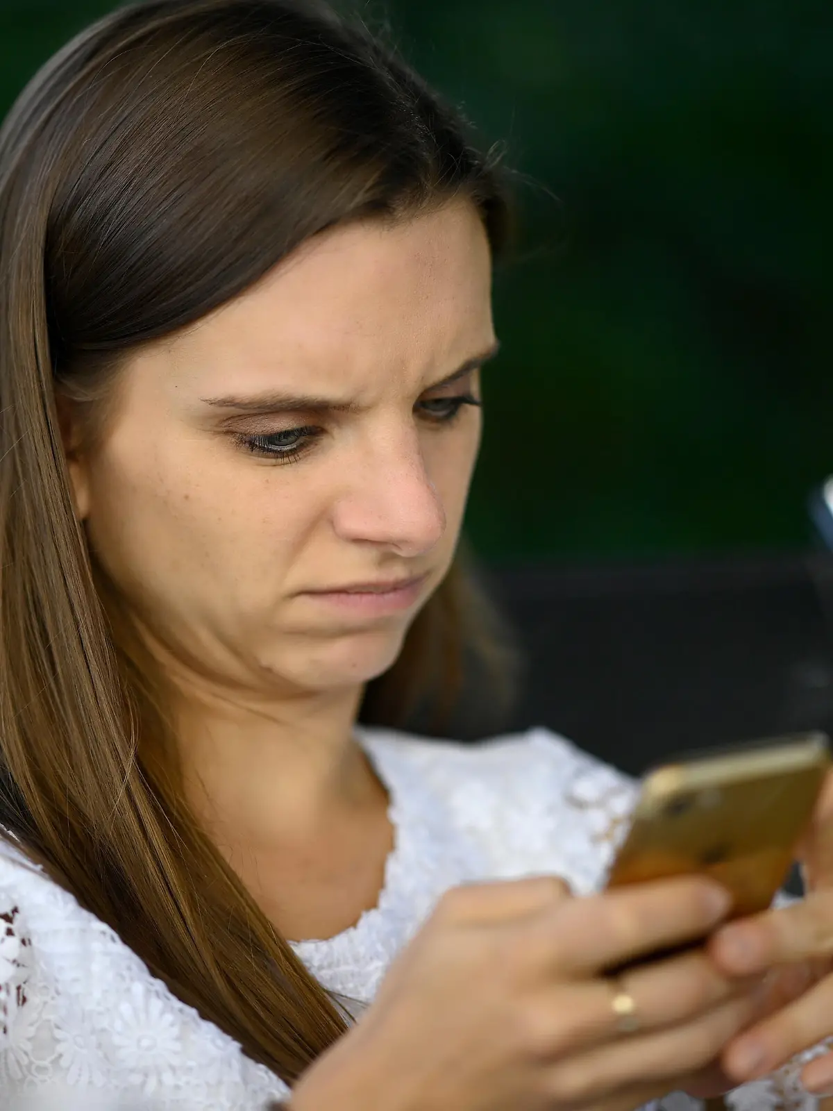 Junge Frau, mit Smartphone, skeptisch, Stuttgart, Baden-Württemberg, Deutschland | Verwendung weltweit